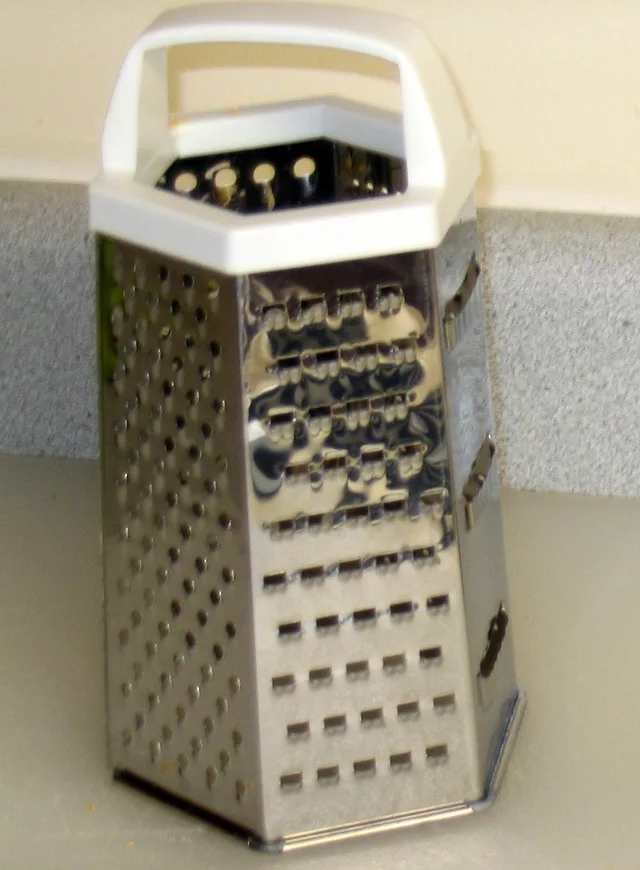 White-handled box grater with several visible cutting surfaces