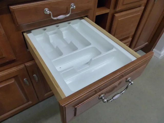 Empty white compartment organiser inside an open wooden kitchen drawer
