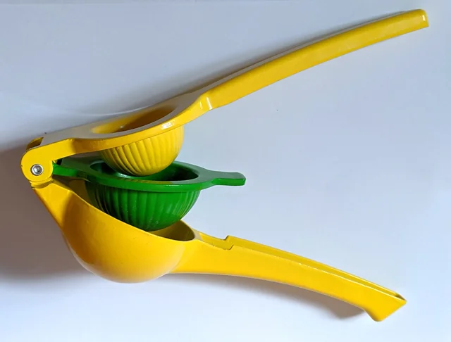 Open yellow handheld citrus squeezer with a green hinged inner bowl