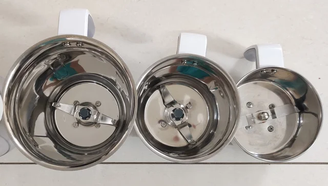 Three open metal mixer-grinder jars with different blade arrangements visible