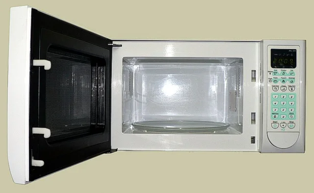 Open microwave with a glass turntable, empty cavity and control panel