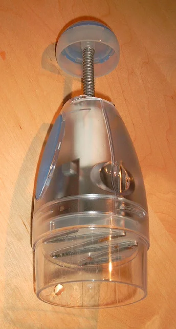 Manual push chopper with a raised plunger, exposed spring and transparent lower chamber