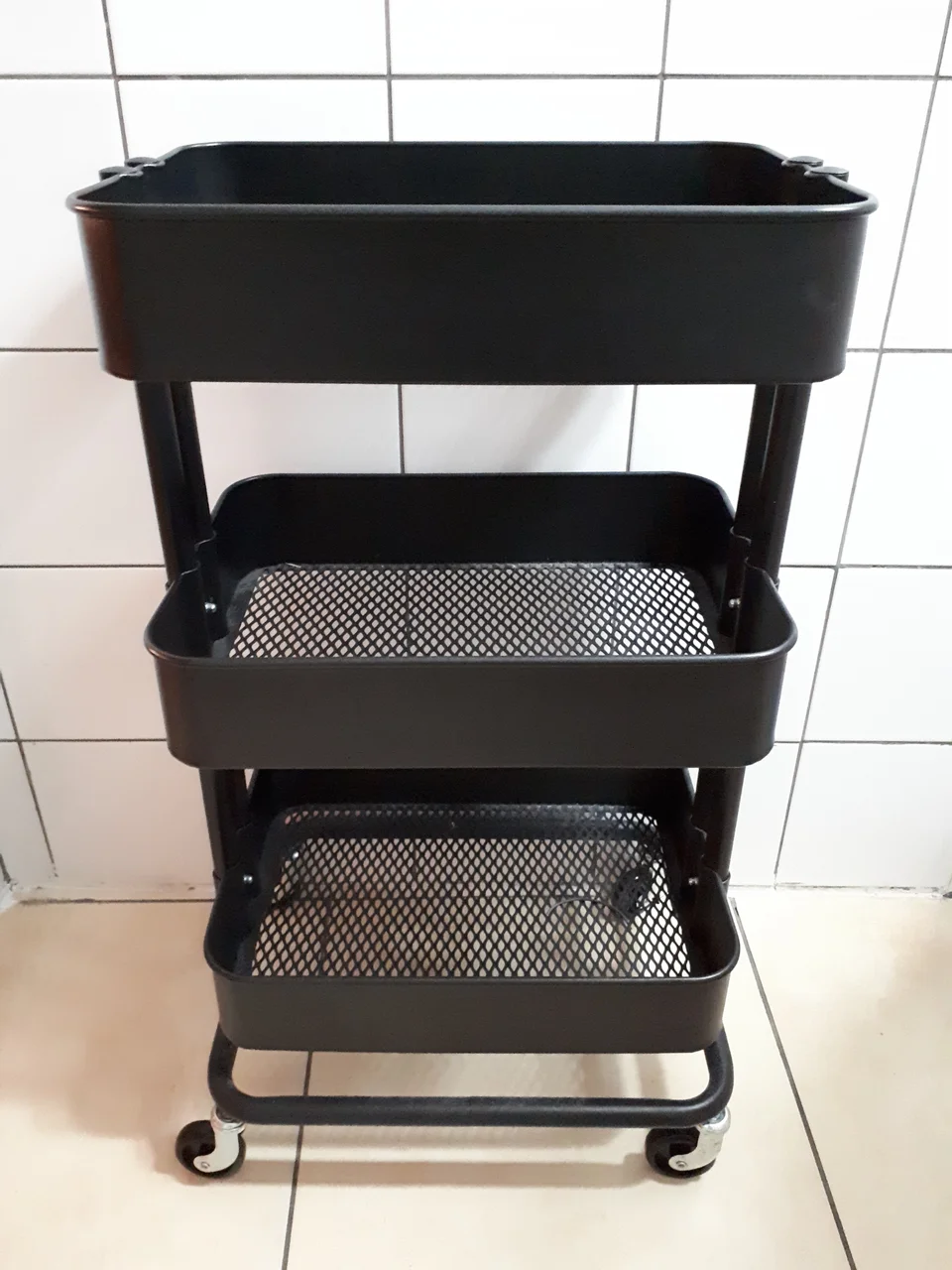 Historical black IKEA RASKOG trolley with three mesh baskets and castor wheels