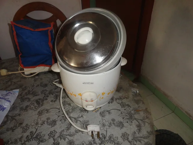 White electric rice cooker with a metal lid and disconnected power plug