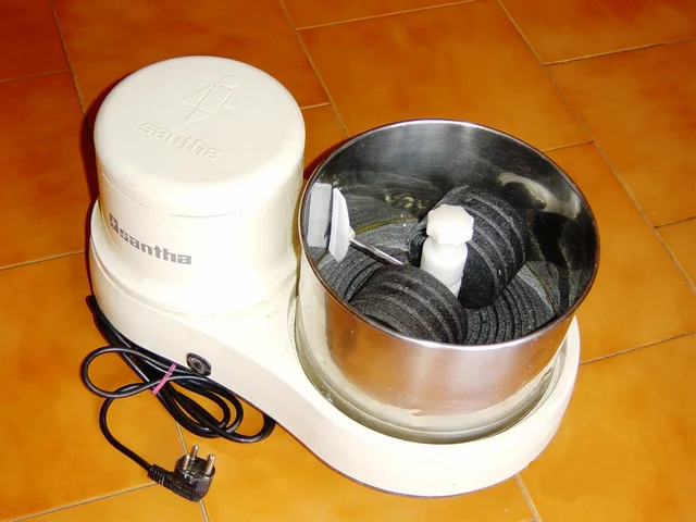 Older white wet grinder with open steel drum, two cylindrical rollers and a disconnected plug